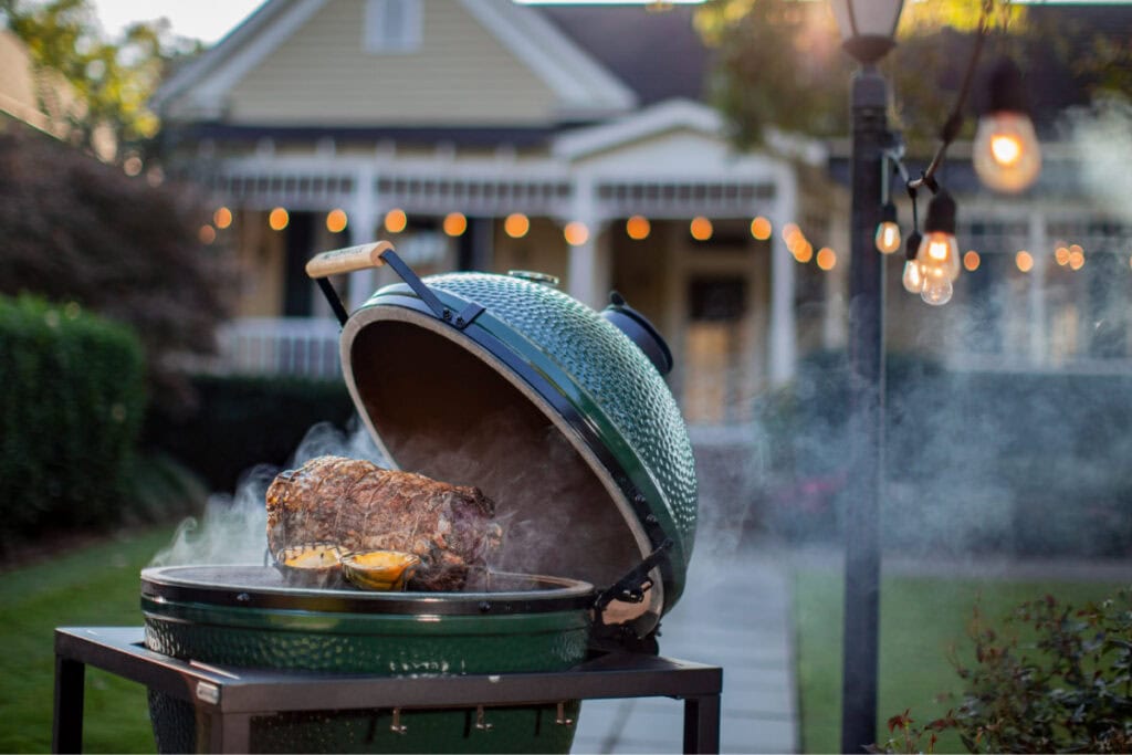 Sizzling outdoor BBQ grill with a roasted meat, set in a cozy backyard with string lights ambiance.