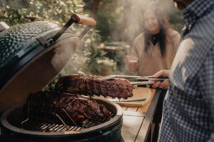 Juicy barbecue ribs cooking on a smoker grill during outdoor gathering.
