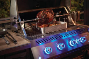 Juicy roast beef cooking on a propane grill with blue LED control knobs at night.